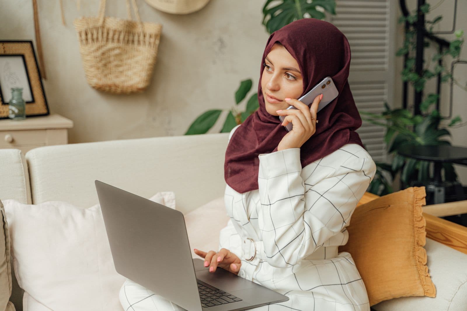 Femme en appel téléphonique tout en travaillant sur son ordinateur portable